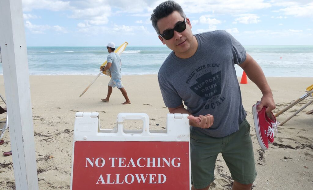 「NO TEACHING ALLOWED（教授禁止）」サインの前でポーズをとるジョージ
